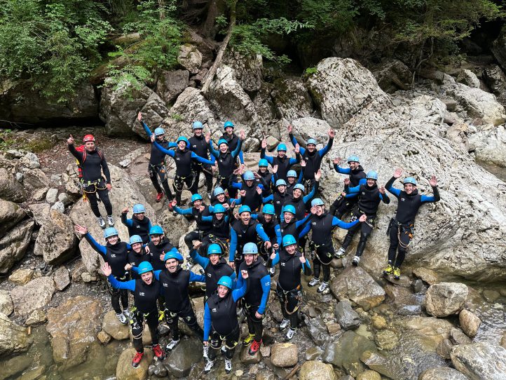 Das dreifive Team beim Canyoning: in schwarz-blauen Neoprenanzügen mit blauen Helmen